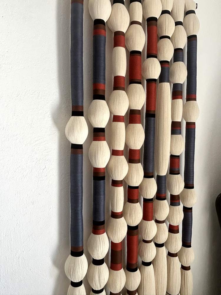Detalle de tapiz de columnas en azul, terracota y negro