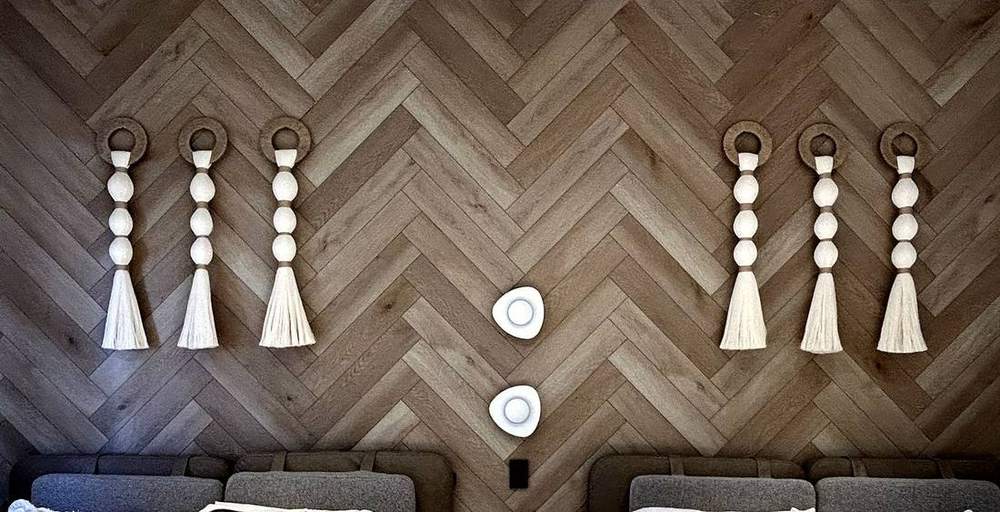 Tótems con aro de yute sobre muro de madera en recámara